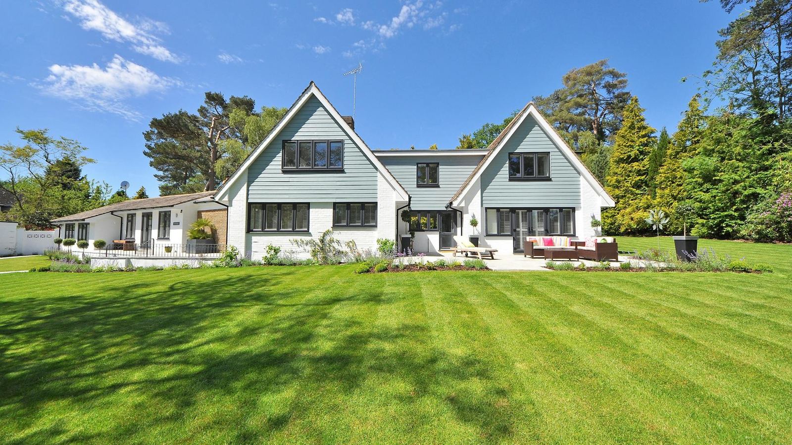 A family home with a freshly tended lawn under blue sky.